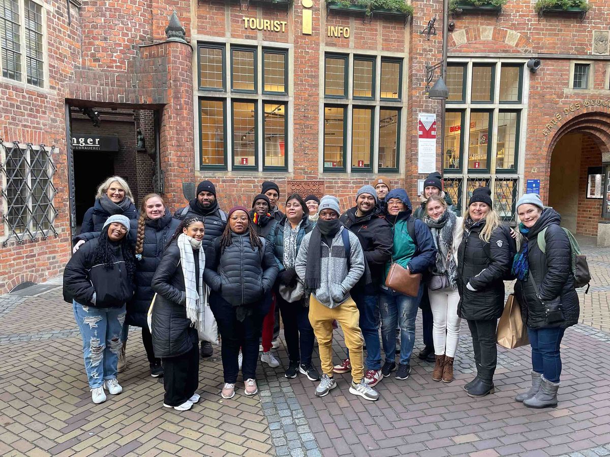 A group of participants at the DAAD Winter School in front of a historic building in Bremen, which houses the Tourist Info.