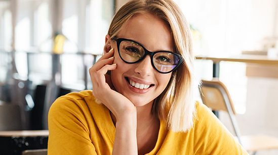 Foto einer schönen glücklichen Frau, die sitzend in die Kamera schaut