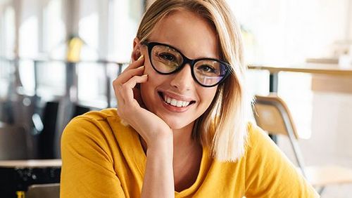 Foto einer schönen glücklichen Frau, die sitzend in die Kamera schaut