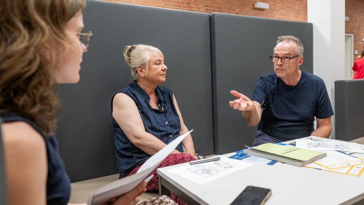 A woman and a man are sitting across from a woman who is noticeably younger than them and are talking with her.