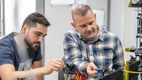 Zwei Männer bauen das Zubehör des Experiments zusammen. 