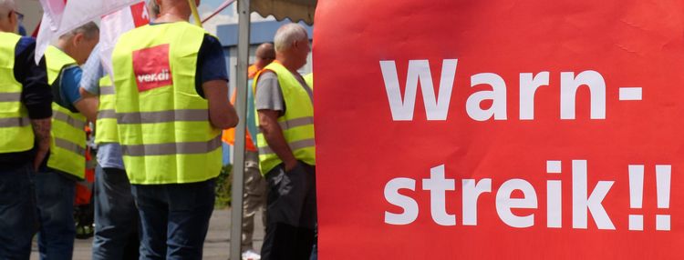 Das Headerbild zeigt ein Teil eines Plakates mit der Aufschrift Warnstreik und im Hintergrund Menschen mit verdi Westen.