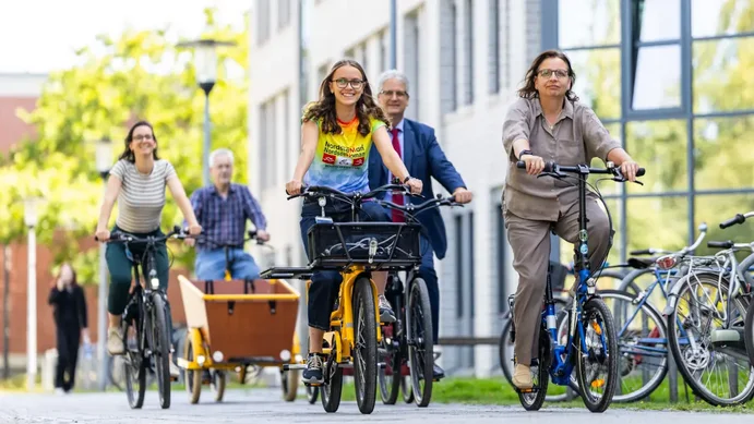 Fünf Personen fahren als Gruppe mit Fahrrädern über den Campus