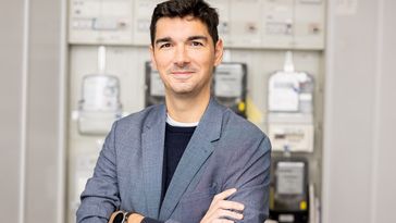 Photo of energy systems researcher Philipp Staudt in front of an electricity meter.