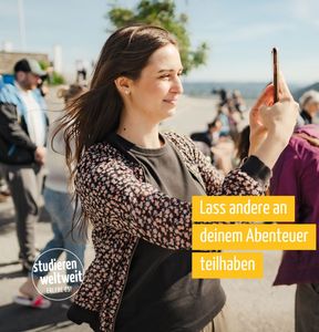 Eine Frau macht in einer Umgebung mit Meer und weiteren Menschen im Hintergrund ein Selfie. Dazu der Aufruf "Lass andere an deinem Abenteuer teilhaben".
