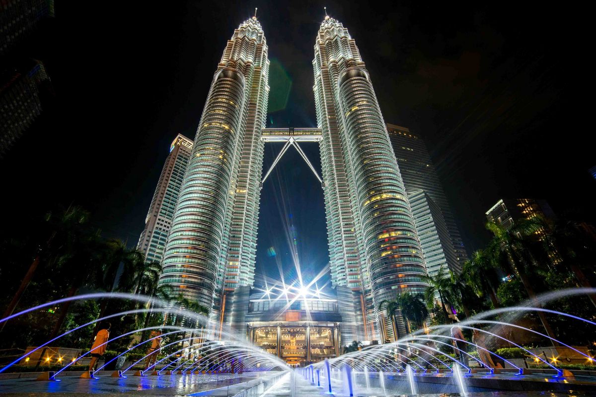 Die Petronas Twin Towers in Kuala Lumpur, Malaysia, bei Nacht. Die Türme sind beleuchtet und ragen majestätisch in den Himmel.