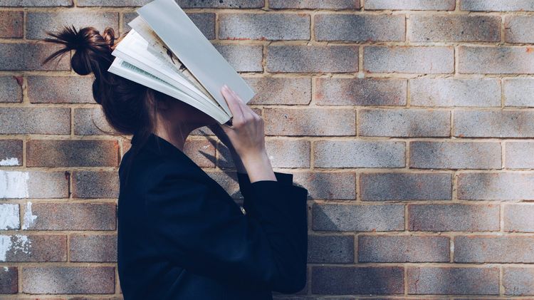 Frau bedeckt ihr Gesicht mit weißem Buch