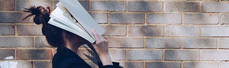 Frau bedeckt ihr Gesicht mit weißem Buch