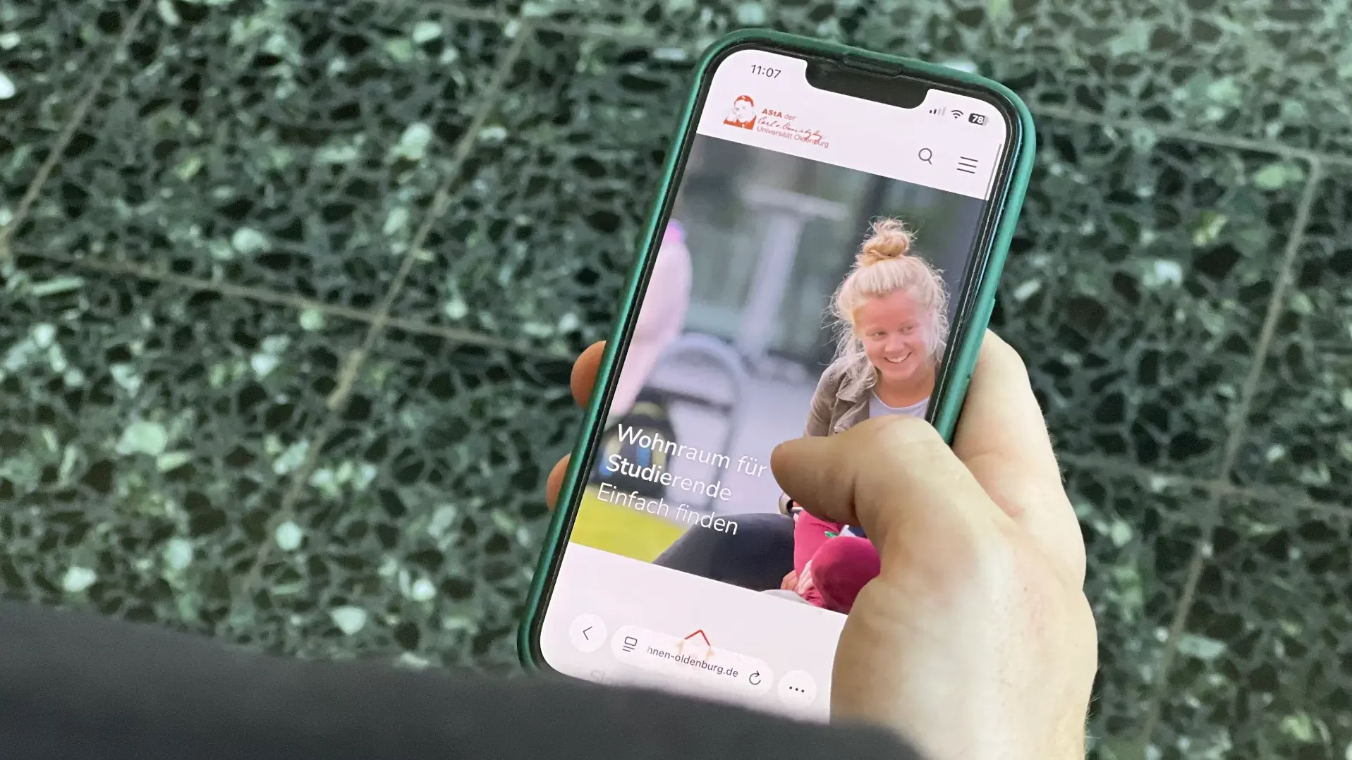 A smartphone displays the home page of the ‘Wohnen Oldenburg’ portal