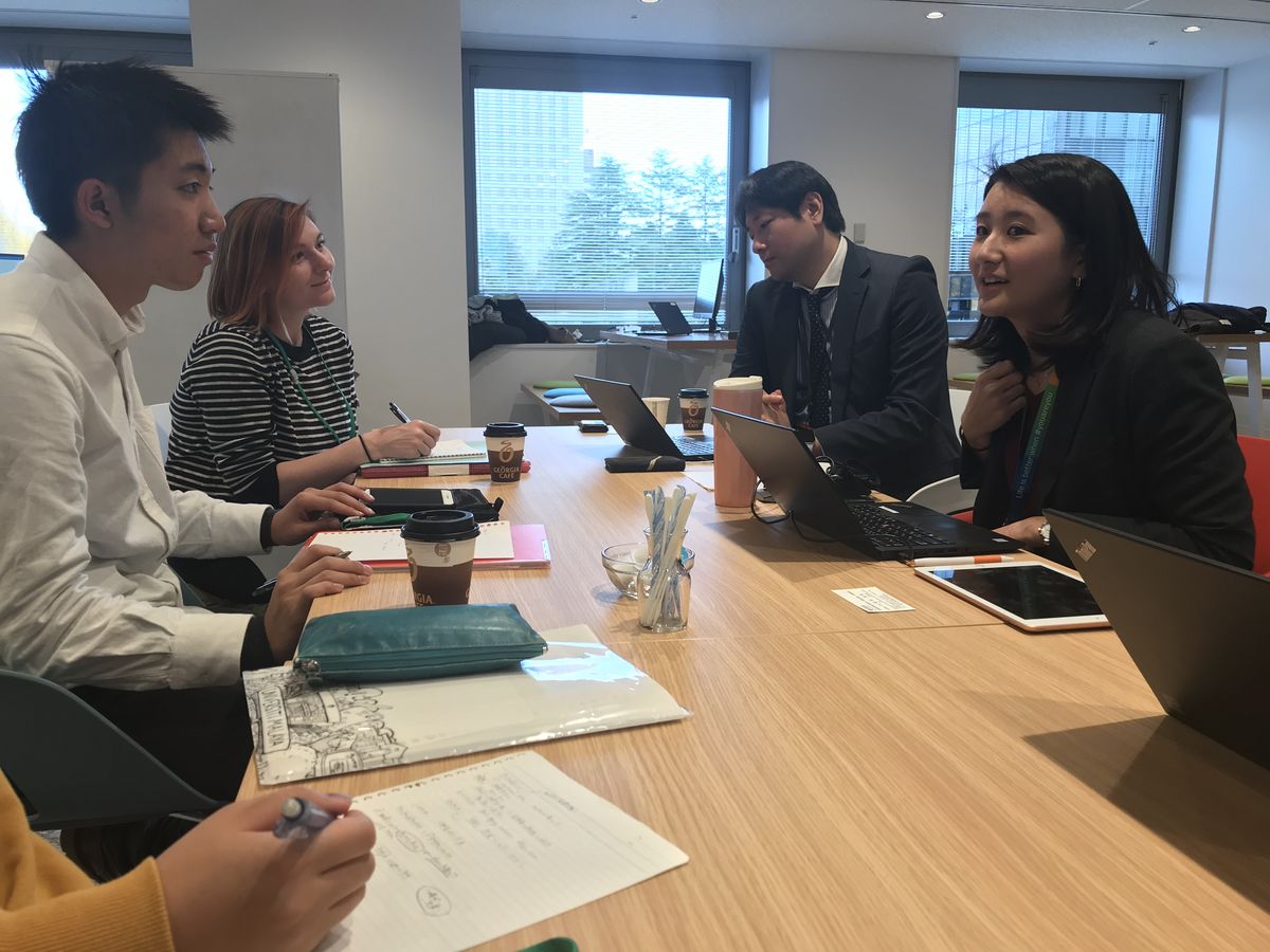 5 Personen die an der Tohoku University an einem Tisch sitzen und sich Unterhalten und Dinge notieren.