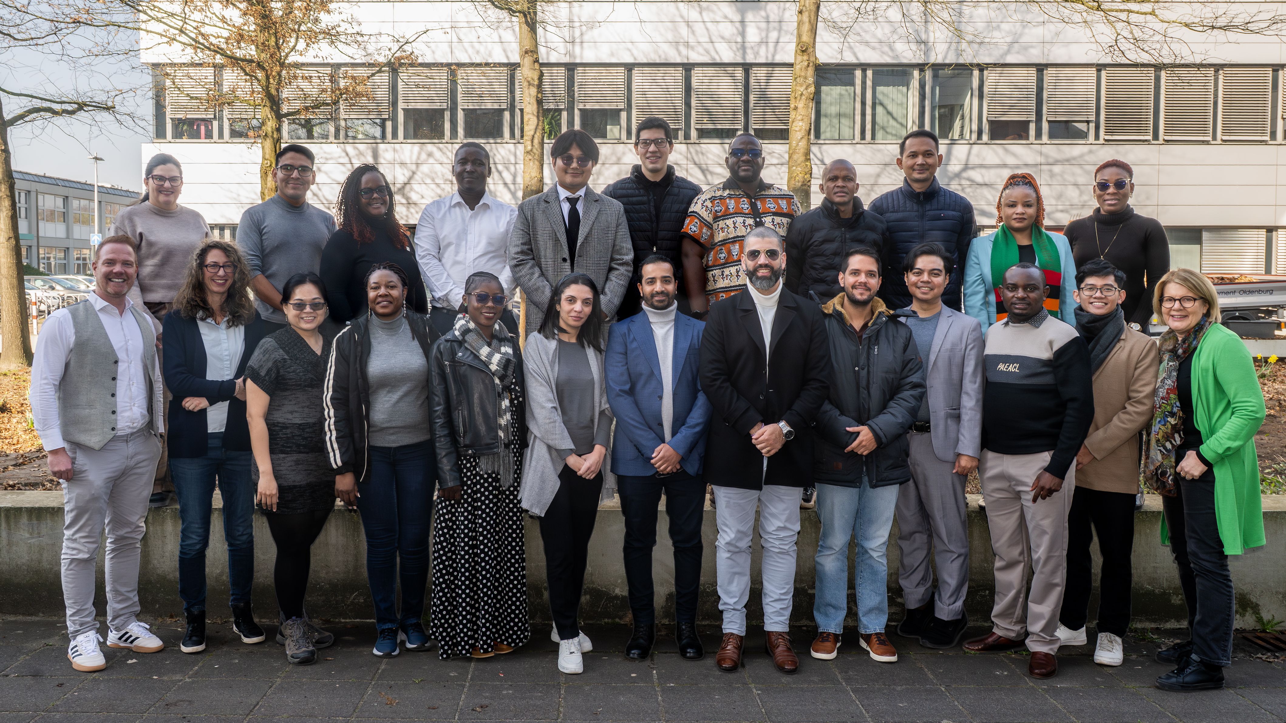A group of adults have positioned themselves for a group photo and are smiling at the camera.