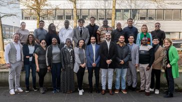 A group of adults have positioned themselves for a group photo and are smiling at the camera.