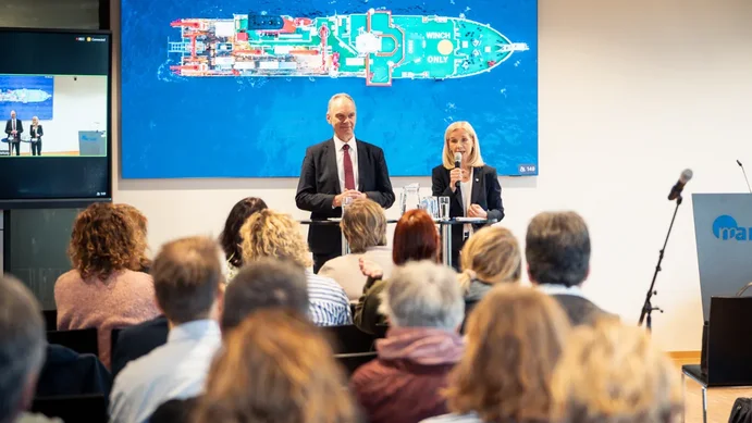 Rektorin Günther spricht in ein Mikrophon, neben ihr Präsident Bruder. Beide stehen zum sitzenden Publikum gewandt, wovon einige Dutzend Personen von hinten im Bild sind.