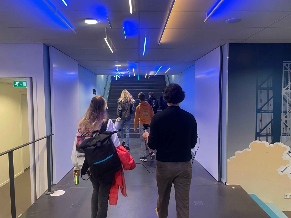 A long, light corridor in the Schule Stad&Esch with blue neon lights and artistic wall painting.