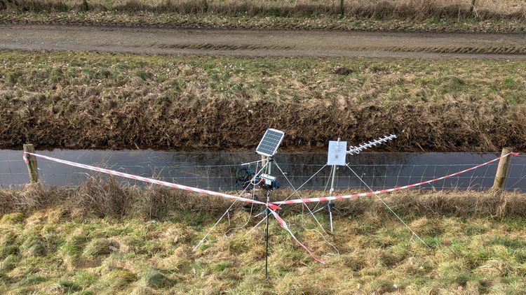 A dyke and a measuring station set up in front of it, cordoned off with tape.