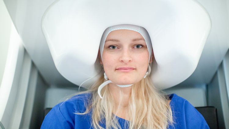 Close-up of test person, whose head disappears under a kind of white hood. 