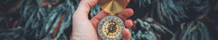 A white person's hand that holds an old fashioned compass