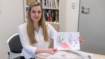 A woman holds a picture in her hand.