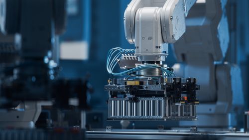 Robot arm places battery pack on a conveyor belt.