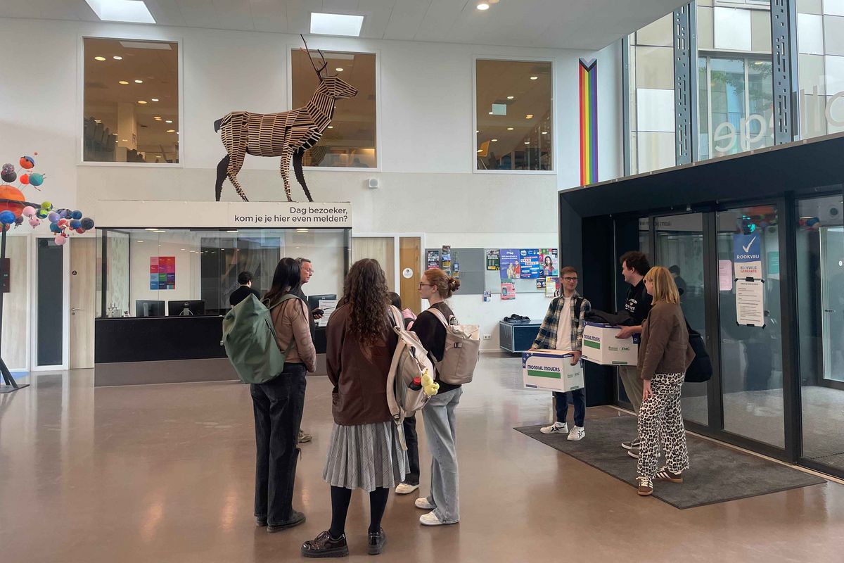 The entrance hall of the Schule Stad&Esch with a life-sized animal statue and a group of young adults.