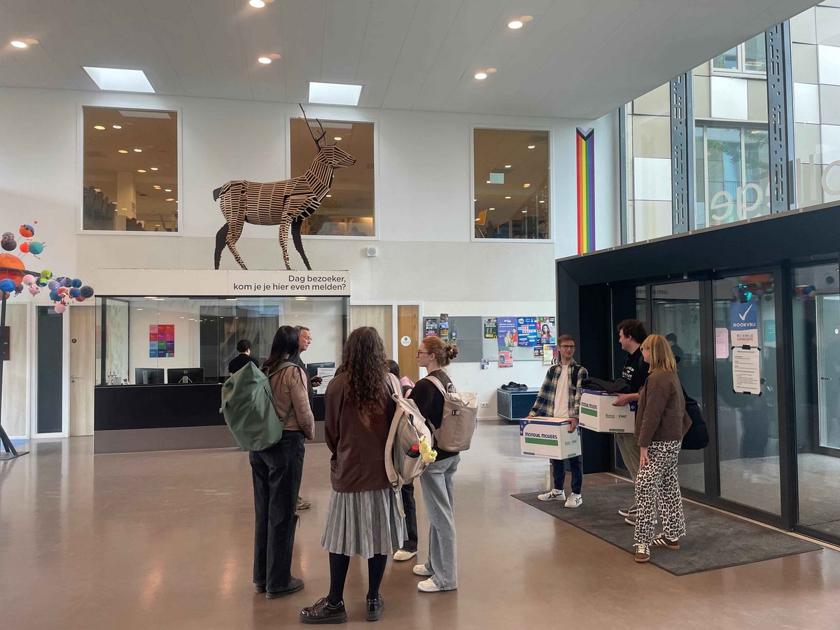 The entrance hall of the Schule Stad&Esch with a life-sized animal statue and a group of young adults.