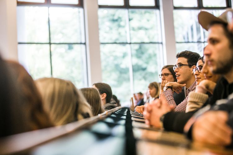 Personen sitzen in einem Hörsaal.