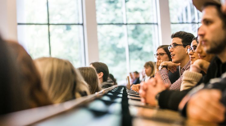 Personen sitzen in einem Hörsaal.