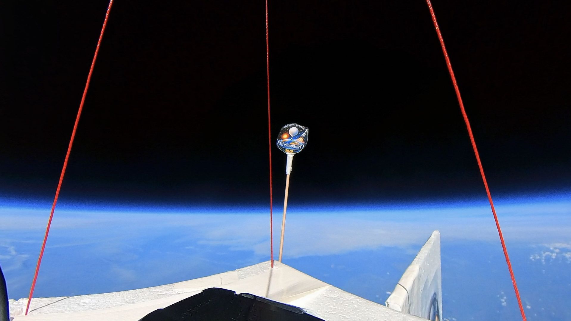 In the background, black space, with the earth below covered by a light blanket of clouds.
