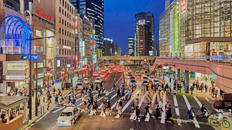 Eine belebte Innenstadtansicht von Tohoku mit vielen Menschen und Autos bei Nacht.