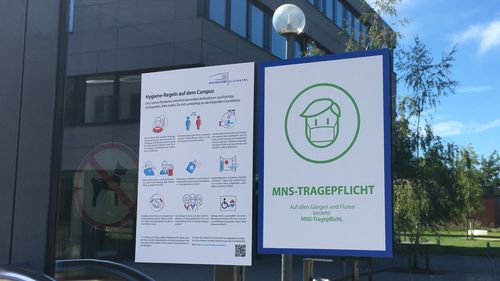 Corona signs at the entrance to a university building.