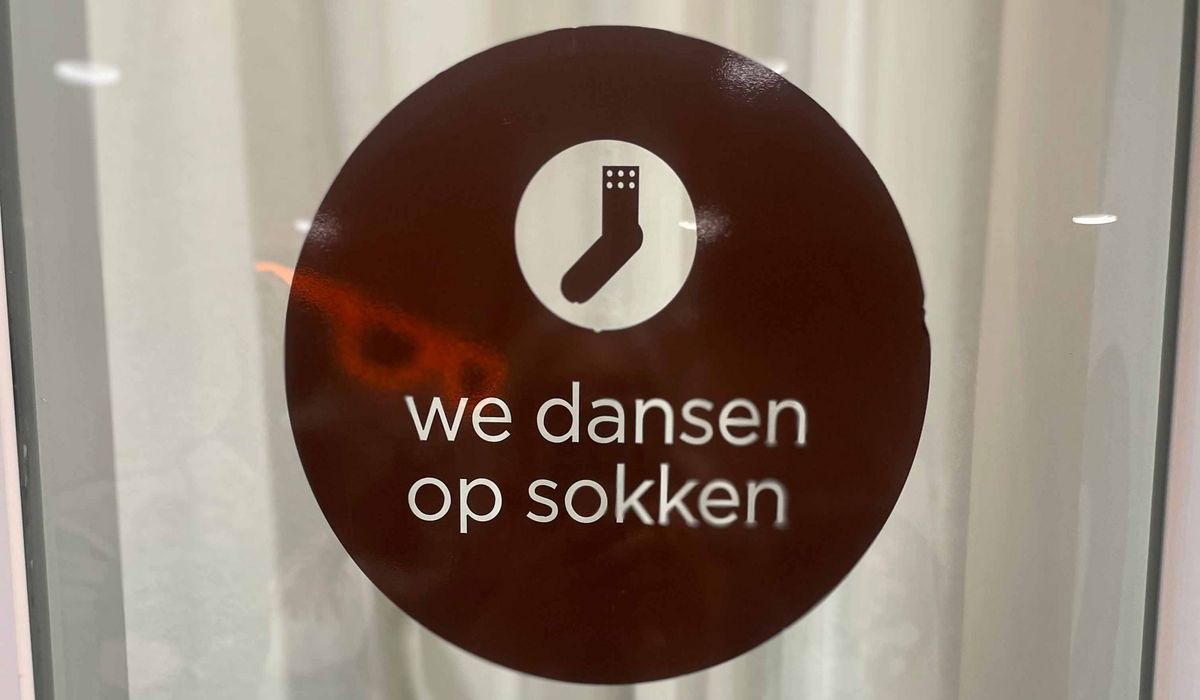 A sign with a white sock symbol and the text "we dansen op sokken".