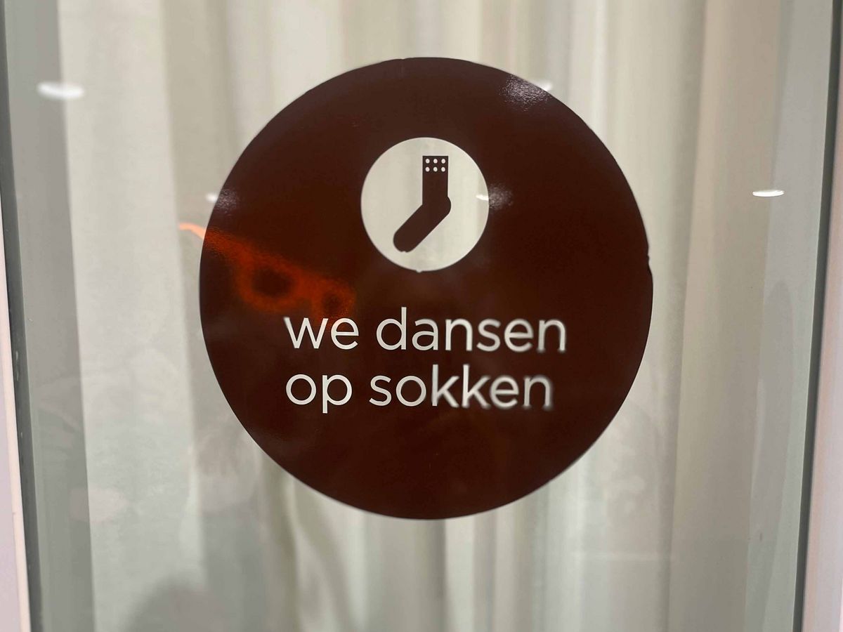 A sign with a white sock symbol and the text "we dansen op sokken".