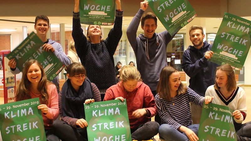 Gruppe von Studierenden im Mensafoyer, die die Plakate zur Klimawoche präsentieren.