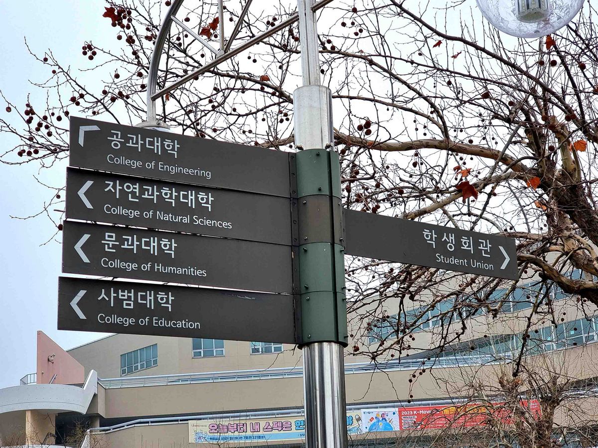 A signpost on the Inha University campus pointing to various colleges and the Students' Union.