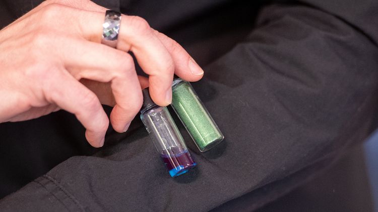 Großaufnahme von zwei kleinen Glasfläschchen vor dunklem Hintergrund.