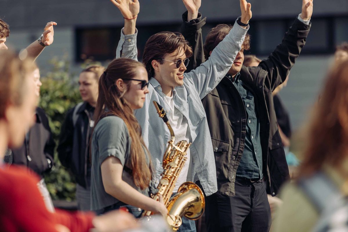 Person von FUNK_U! mit Saxophon im Fokus zwischen dazu klatschende Personen.