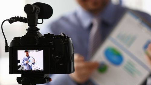 [Translate to English:] man holding a presentation sheet - seen through a camera
