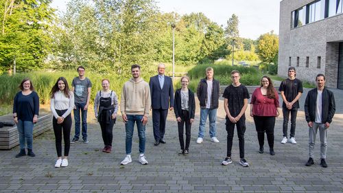 Twelve people stand in a staggered position, with the experimental lecture theatre to the side.
