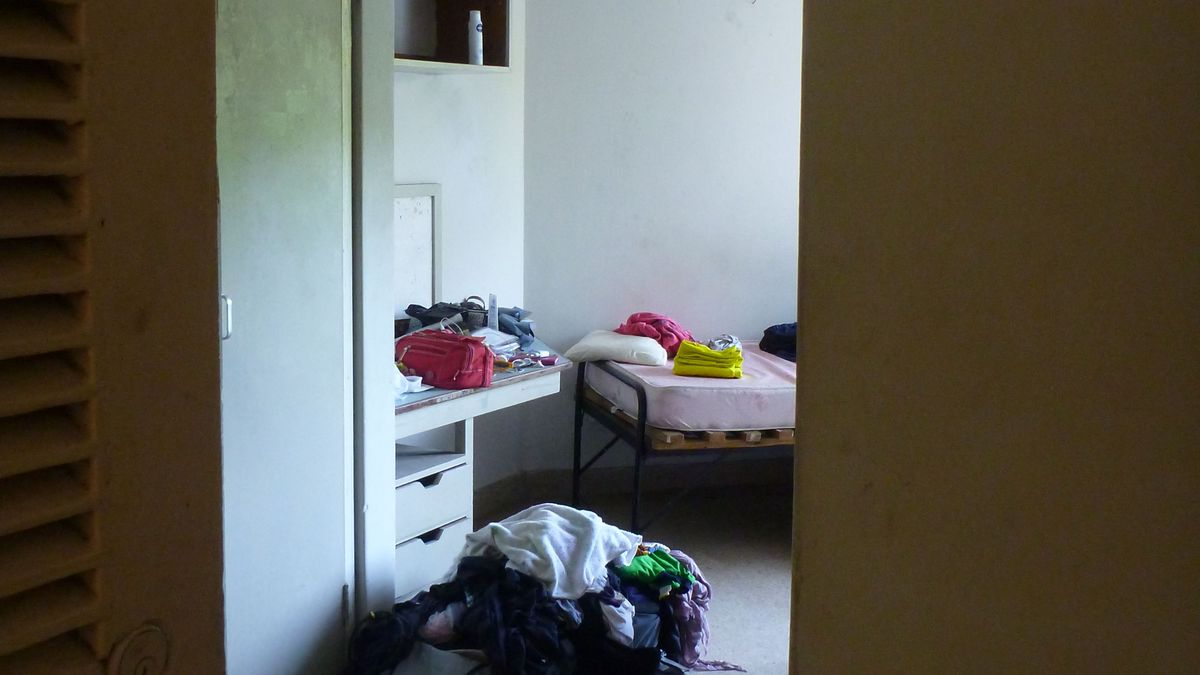 A simple student room with a bed, desk and wardrobe.