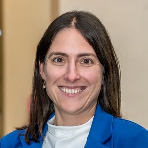 Portrait of Jasmina Sterz. She has brown shoulder-length hair and wears a white shirt and a blue blazer.