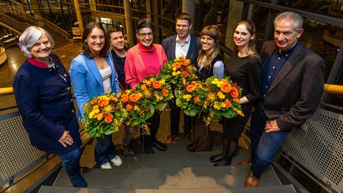 Acht Personen stehen auf der Freitreppe des Hörsaalzentrums, die Preisträgerinnen und Preisträger halten jeweils einen großen Blumenstrauß in der Hand. 