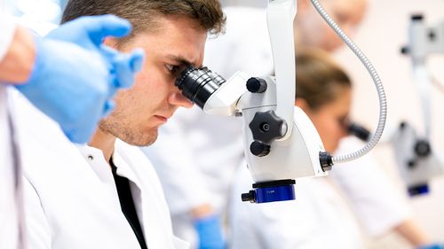 Medical student looks through a microscope