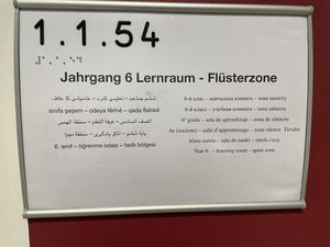 Beschilderung eines Lernraums an der IGS Flötenteich auf 12 Sprachen und Raumnummer auf Brailleschrift