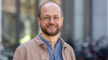 Das Bild zeigt Mario Dunkel. Er steht vor dem Hörsaalgebäude A 14 und lächelt in die Kamera.