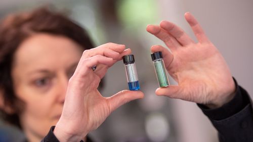 Manuela Schiek holds two vials of the colourant in her hands.