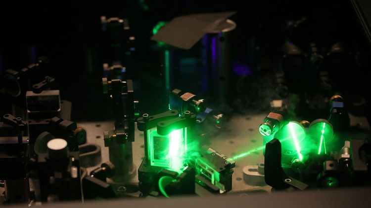 Ein grüner Laserstrahl wird von Spiegeln und Linsen durch eine Versuchsanordnung geleitet.