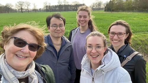 Five people in front of a meadow. 