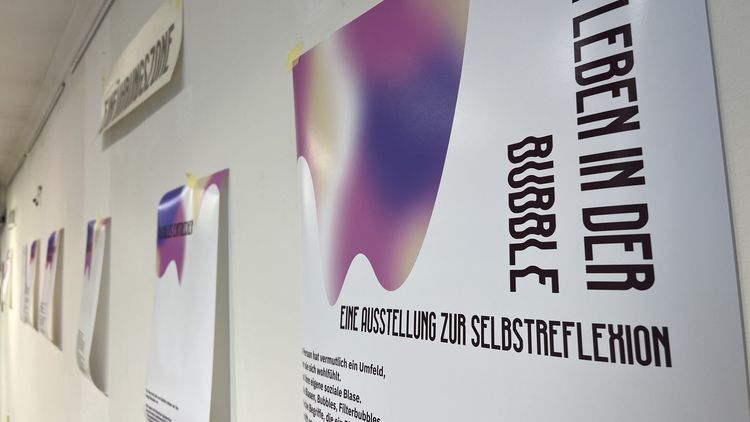 Mehrere Ausstellungsplakate hängen an einer Wand