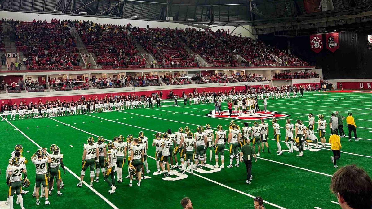 American Football-Spiel in einem großen, überdachten Stadion mit vielen Zuschauer*innen.