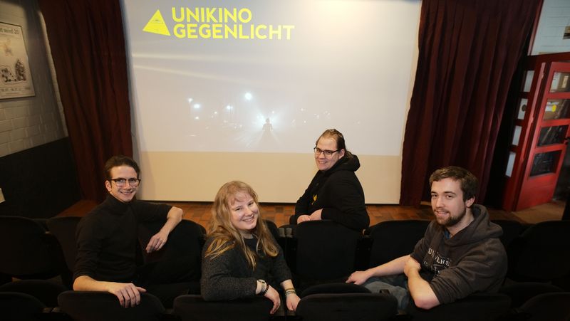 Das Foto zeigt Philip Kaufmann, Martina Höger, Justin Klimek und Benjamin Witte vor einer Kinoleinwand